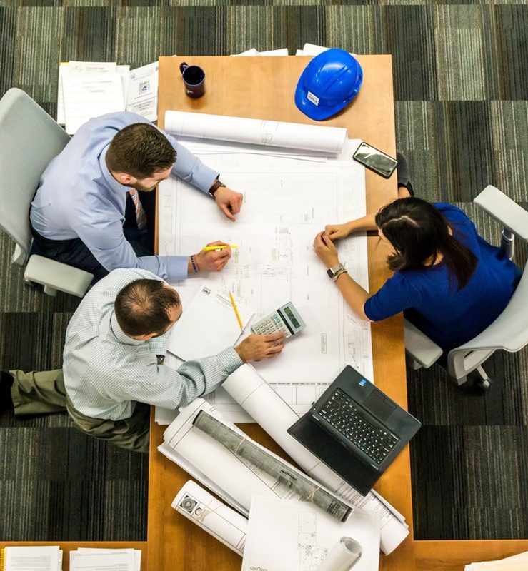 three people working at a table with blueprints